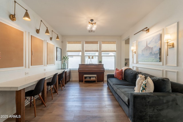 living area featuring hardwood / wood-style flooring, a chandelier, and baseboards