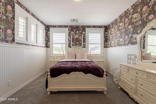 carpeted bedroom with a wainscoted wall, multiple windows, wallpapered walls, and baseboards