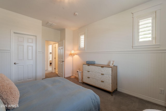 carpeted bedroom featuring wainscoting and baseboards