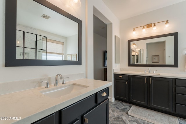 full bathroom featuring brick patterned floors, two vanities, and walk in shower