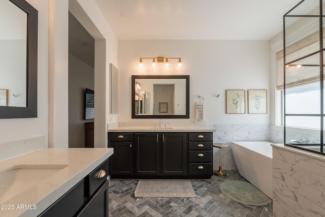 full bathroom featuring a freestanding bath, two vanities, and brick patterned flooring
