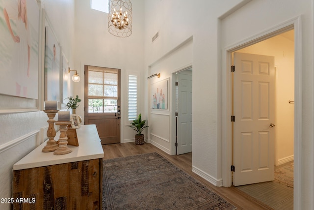entrance foyer with light wood-style flooring, a chandelier, and baseboards