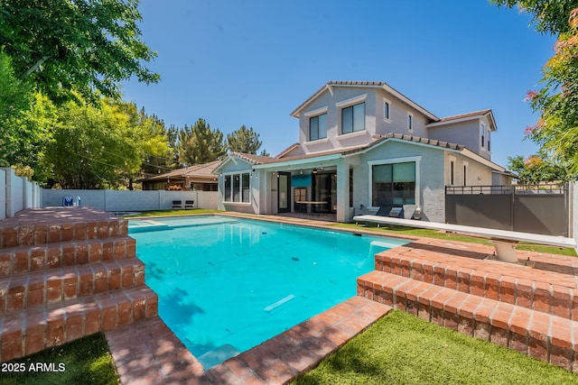 rear view of house featuring a fenced backyard, stucco siding, a patio area, and a tile roof