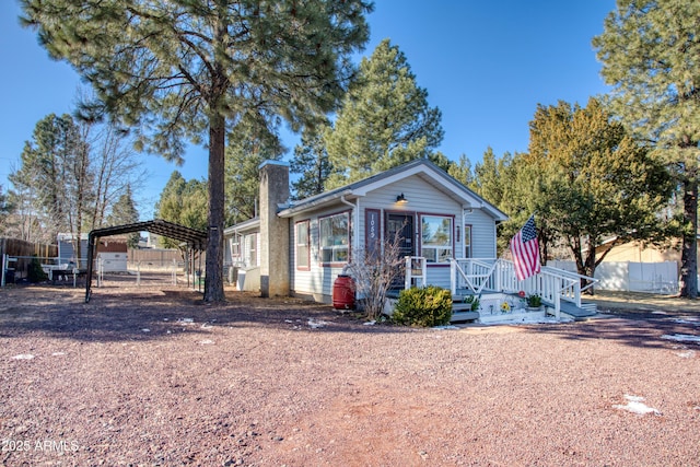 view of front facade with a carport, driveway, a chimney, and fence