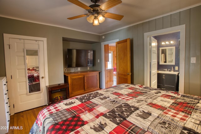 bedroom with ensuite bathroom, crown molding, a ceiling fan, and wood finished floors