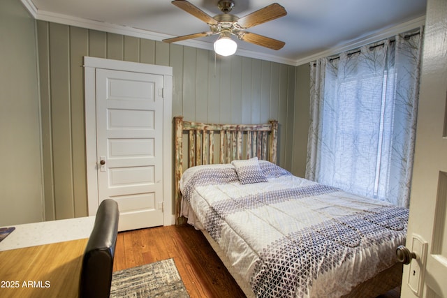 bedroom with wood finished floors, a ceiling fan, and ornamental molding