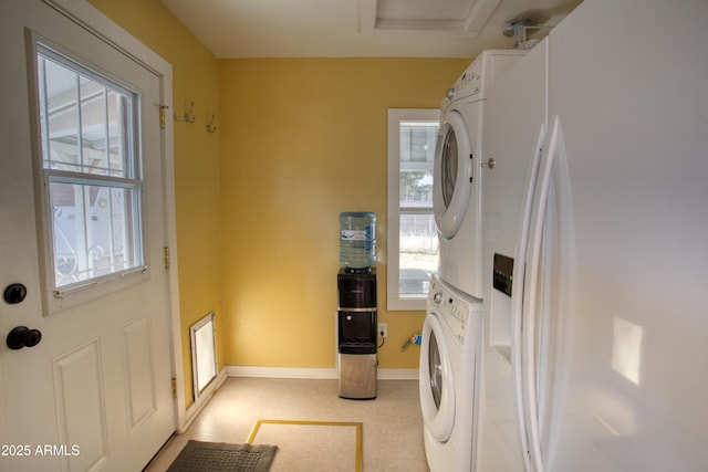 washroom with laundry area, baseboards, and stacked washer and dryer