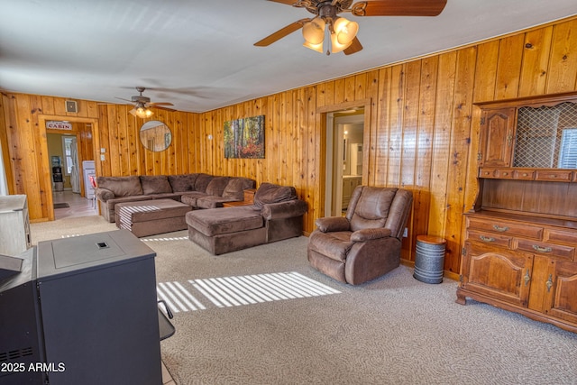 carpeted living area featuring a ceiling fan and wood walls