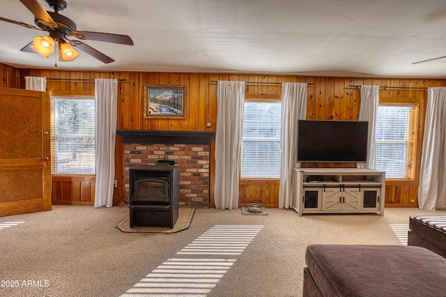 carpeted living area with plenty of natural light, wooden walls, and a wood stove