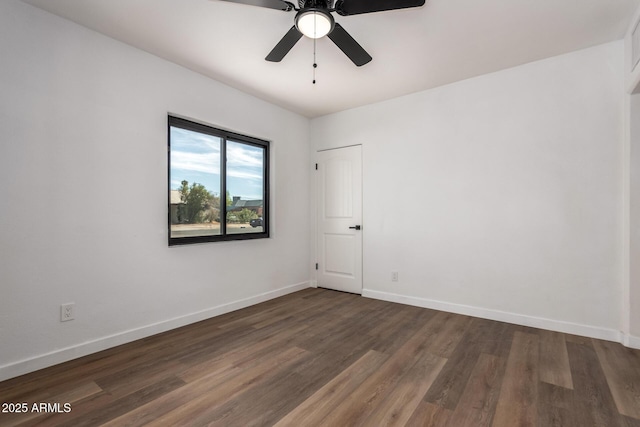 unfurnished room featuring baseboards, dark wood finished floors, and a ceiling fan