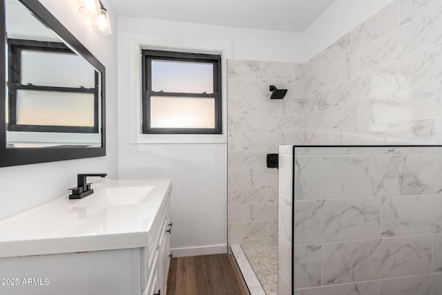 full bathroom with walk in shower, vanity, baseboards, and wood finished floors