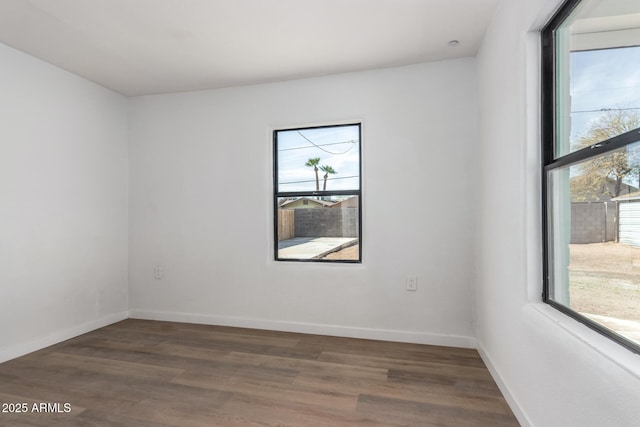 spare room with dark wood-style flooring and baseboards