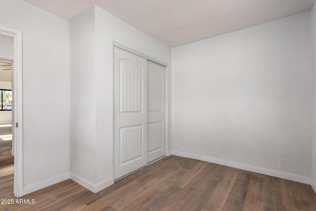 unfurnished bedroom with a closet, baseboards, and wood finished floors