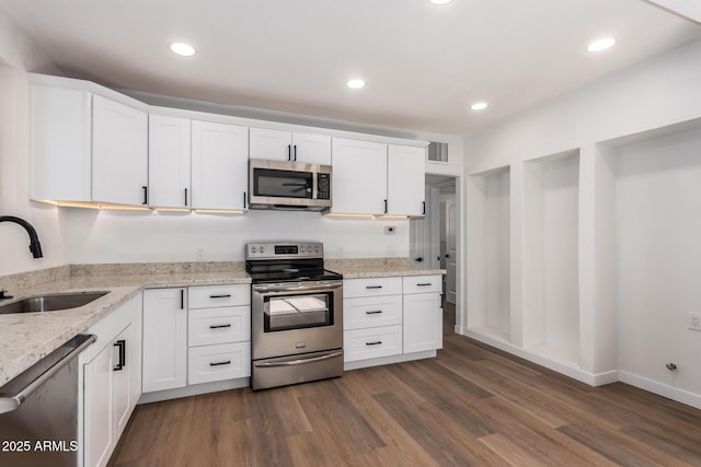 kitchen with appliances with stainless steel finishes, a sink, visible vents, and white cabinets