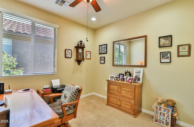 office space featuring a ceiling fan, light colored carpet, visible vents, and plenty of natural light