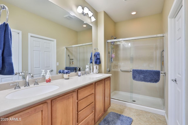 bathroom with double vanity, a shower stall, visible vents, and a sink