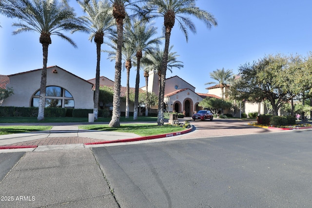 exterior space featuring decorative driveway, a front yard, and stucco siding