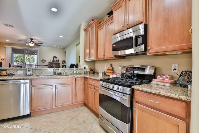 kitchen with light tile patterned floors, light stone counters, a sink, visible vents, and appliances with stainless steel finishes