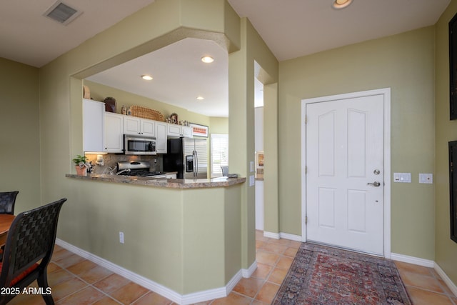 kitchen featuring white cabinetry, decorative backsplash, light tile patterned floors, kitchen peninsula, and stainless steel appliances