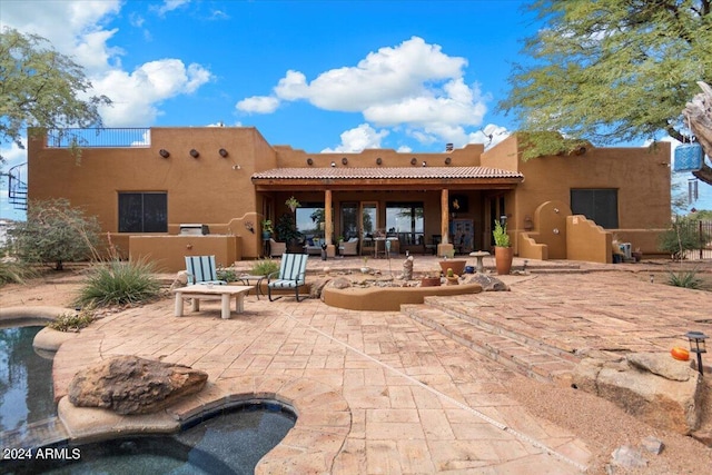 back of house featuring a hot tub and a patio area