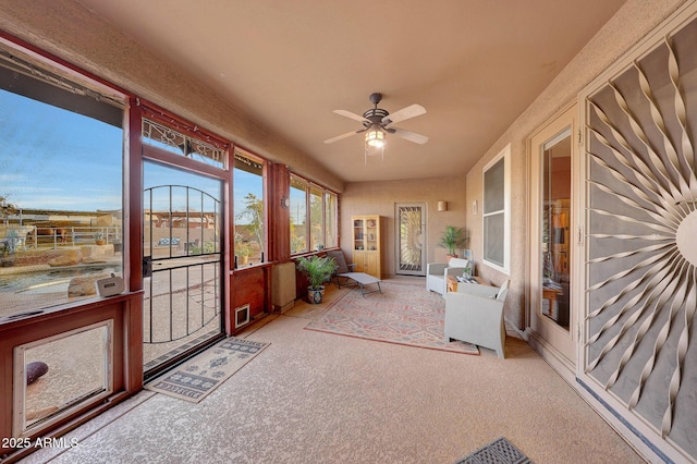 unfurnished sunroom featuring ceiling fan