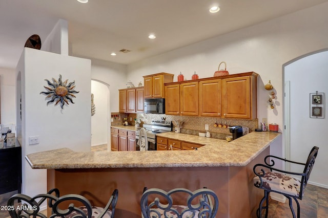 kitchen with decorative backsplash, a kitchen bar, kitchen peninsula, and stainless steel range with electric cooktop