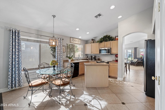 kitchen with appliances with stainless steel finishes, vaulted ceiling, pendant lighting, light brown cabinets, and a kitchen island