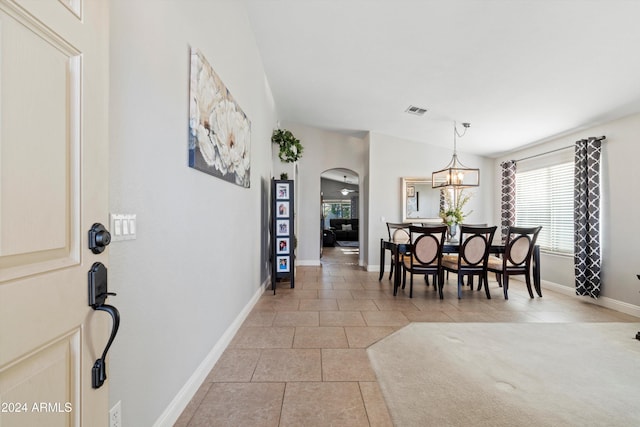 tiled dining space featuring vaulted ceiling and an inviting chandelier