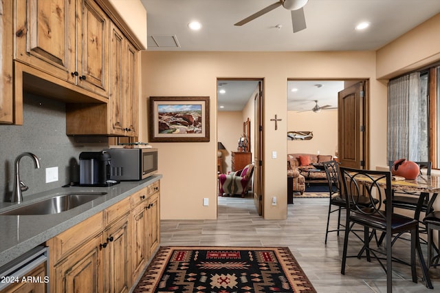 kitchen featuring decorative backsplash, appliances with stainless steel finishes, light wood-type flooring, ceiling fan, and sink