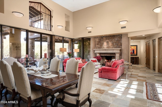 dining space with a towering ceiling and a stone fireplace