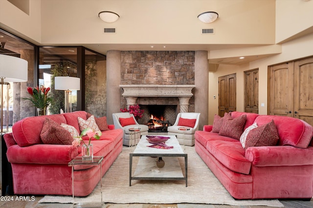 living room with a stone fireplace and a towering ceiling