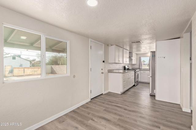 kitchen with white cabinetry, appliances with stainless steel finishes, wood-type flooring, and a textured ceiling