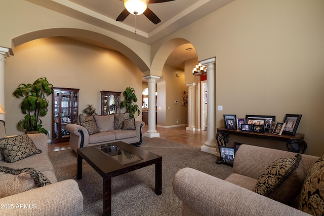 living room with ceiling fan, a towering ceiling, and ornate columns