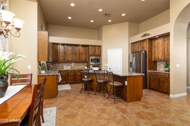 kitchen featuring tasteful backsplash, sink, a center island, light stone counters, and stainless steel appliances