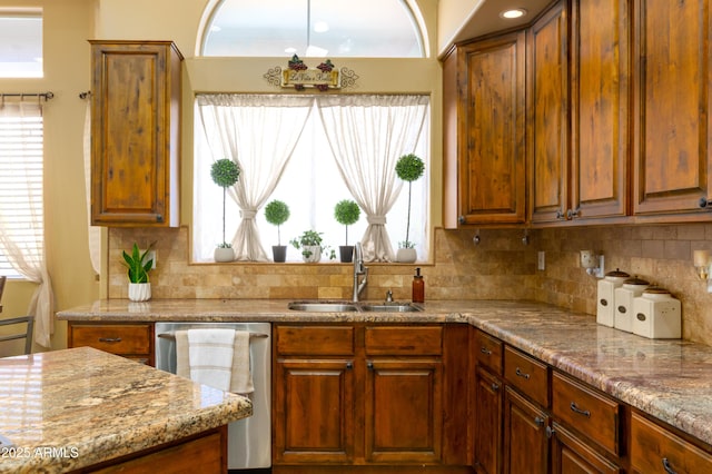 kitchen with dishwasher, sink, backsplash, and light stone counters