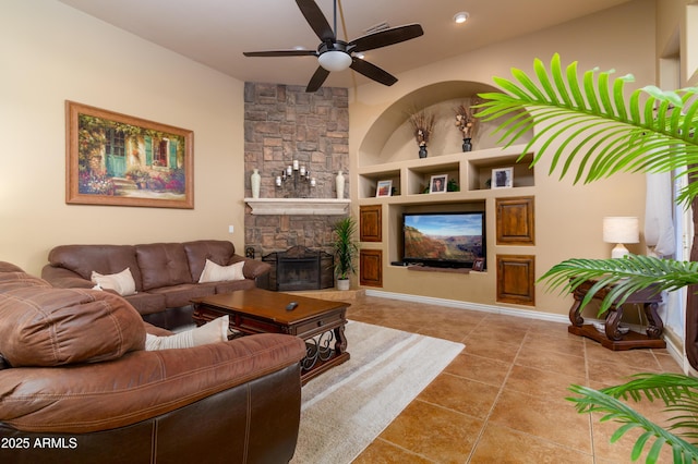 living room featuring built in shelves, ceiling fan, a stone fireplace, and light tile patterned floors