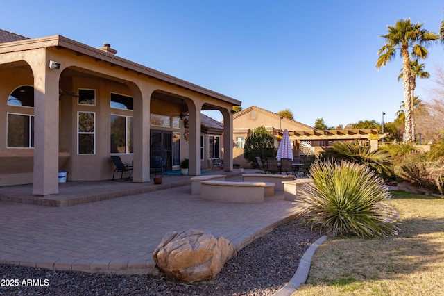 back of property with a fire pit and a patio