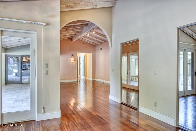 empty room featuring vaulted ceiling with beams, french doors, wood ceiling, and wood-type flooring