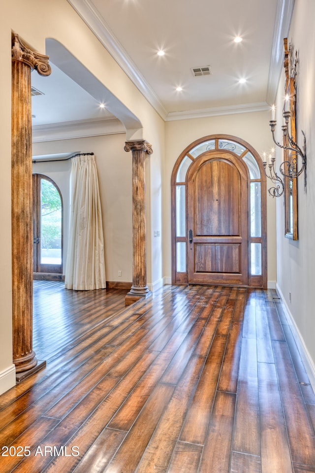 foyer featuring ornate columns, crown molding, and dark hardwood / wood-style floors