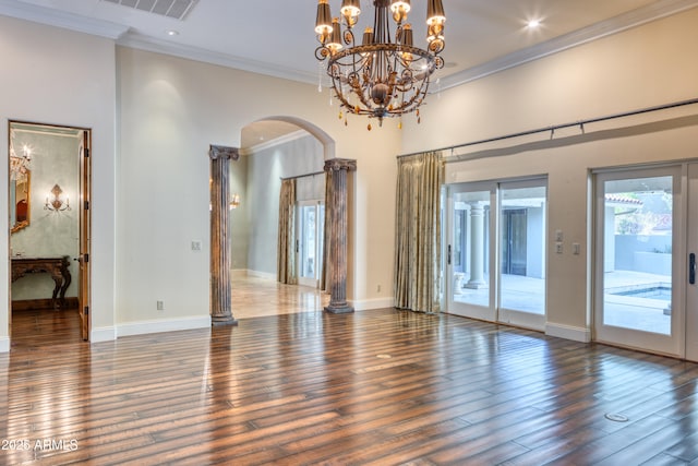 empty room featuring dark hardwood / wood-style floors, crown molding, and a notable chandelier