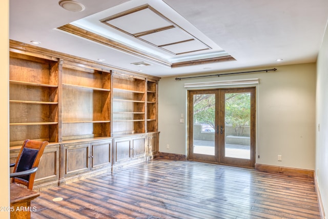 unfurnished office with a raised ceiling, dark hardwood / wood-style flooring, built in features, french doors, and ornamental molding