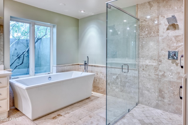 bathroom with plus walk in shower, tile walls, and vanity