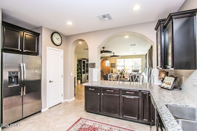 kitchen with ceiling fan, light stone countertops, stainless steel fridge with ice dispenser, backsplash, and light tile patterned floors