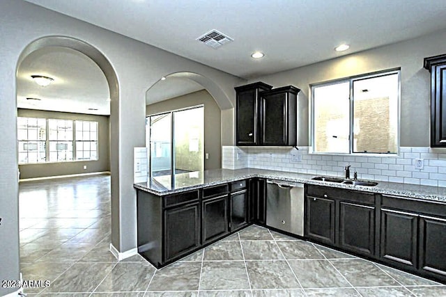 kitchen with decorative backsplash, light stone counters, stainless steel dishwasher, sink, and light tile patterned floors