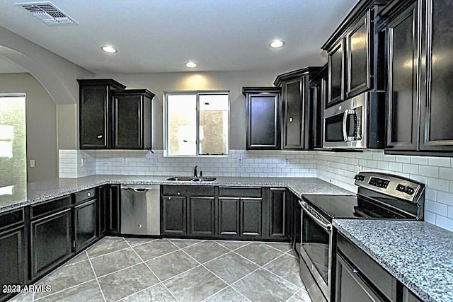 kitchen with decorative backsplash, sink, light tile patterned floors, and stainless steel appliances