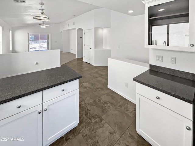 kitchen with white cabinetry, ceiling fan, decorative light fixtures, and dark stone counters