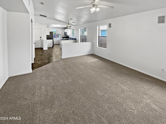 unfurnished living room featuring lofted ceiling, dark colored carpet, and ceiling fan