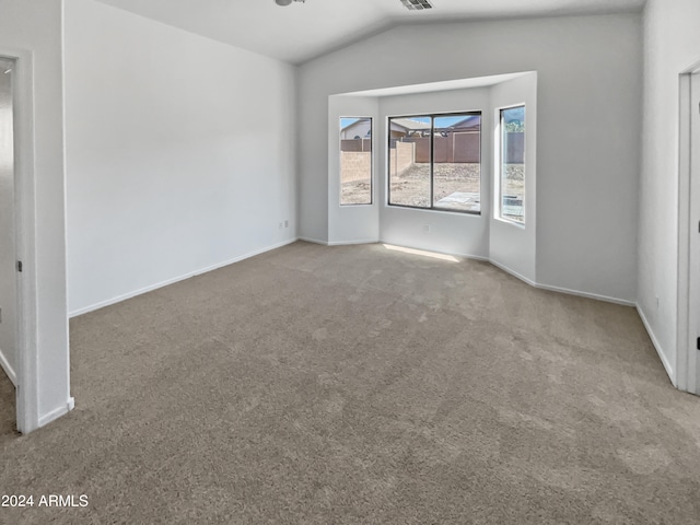 carpeted empty room with vaulted ceiling