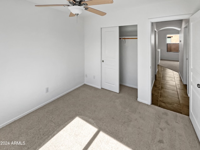 unfurnished bedroom featuring a closet, light colored carpet, and ceiling fan