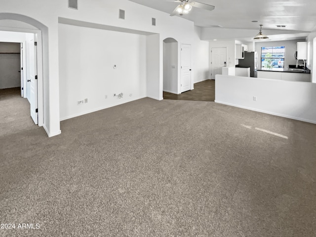 unfurnished living room with ceiling fan, sink, and dark colored carpet